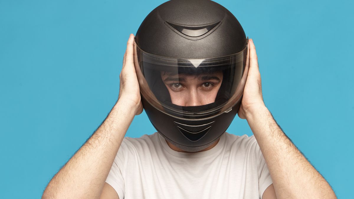 موتورسوار با کلاه کاسکت که به‌دلیل فشار روی گردن و شانه‌ها دچار خستگی و گردن‌درد شده است